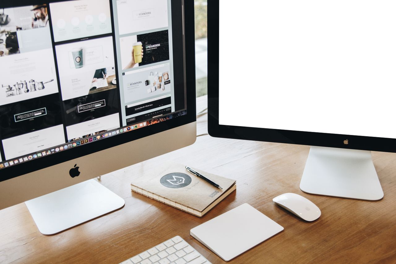 Overhead perspective of a chic office setup showcasing two monitors, keyboard, mouse, and contemporary desk items.